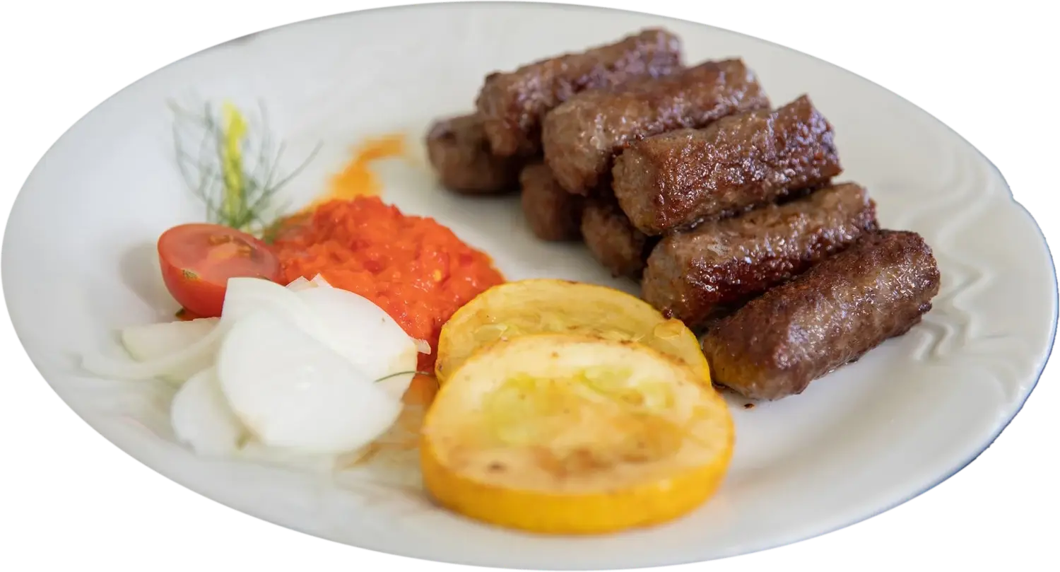 Ćevapi na bijelom tanjiru, uz ajvar i luk